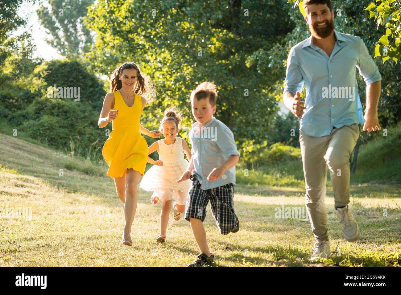 Aktive junge Eltern mit einem gesunden Lebensstil zusammen mit ihren zwei Kindern im freien Wettbewerb in einem Sommertag Stockfoto