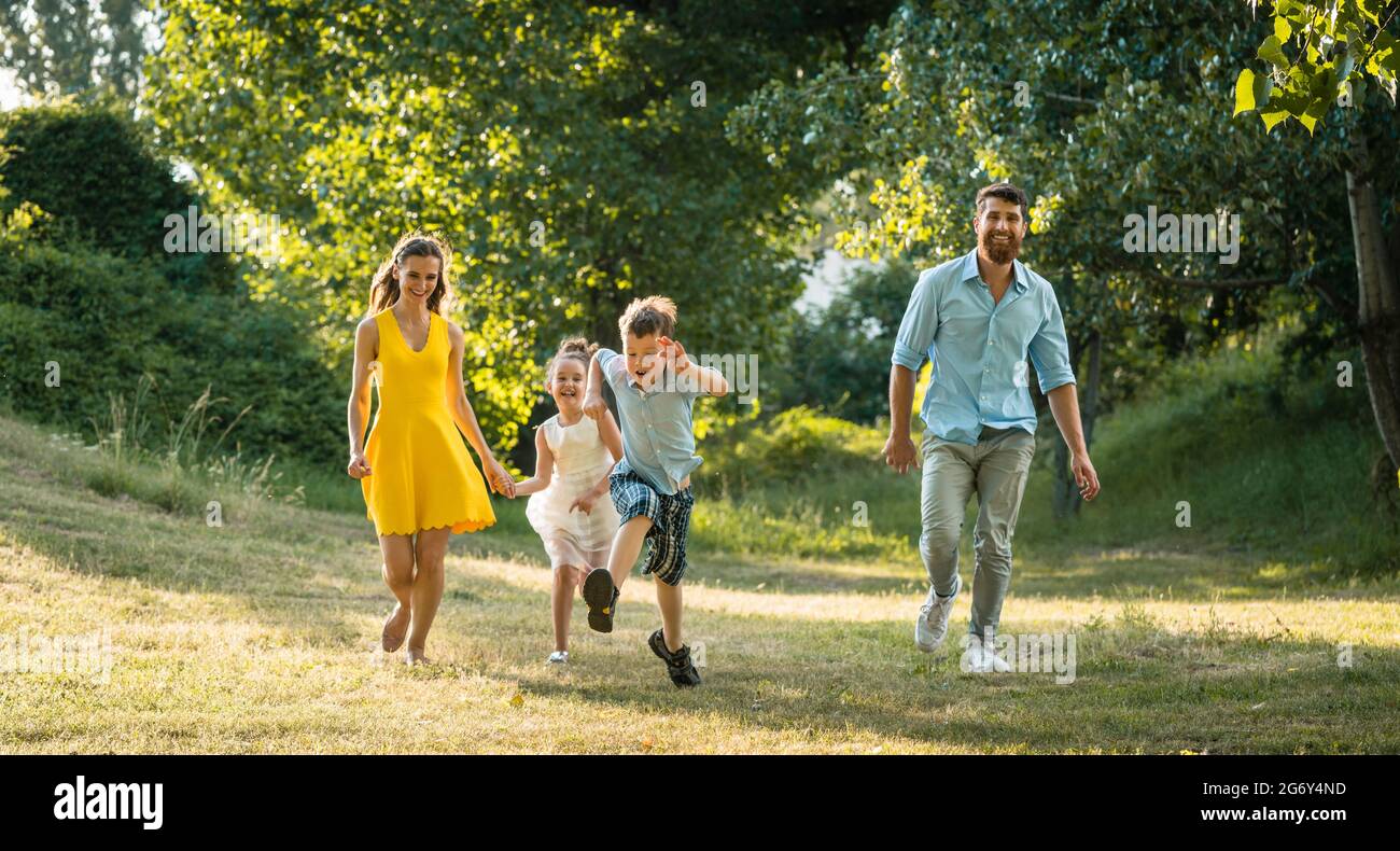 Aktive junge Eltern mit einem gesunden Lebensstil zusammen mit ihren zwei Kindern im freien Wettbewerb in einem Sommertag Stockfoto