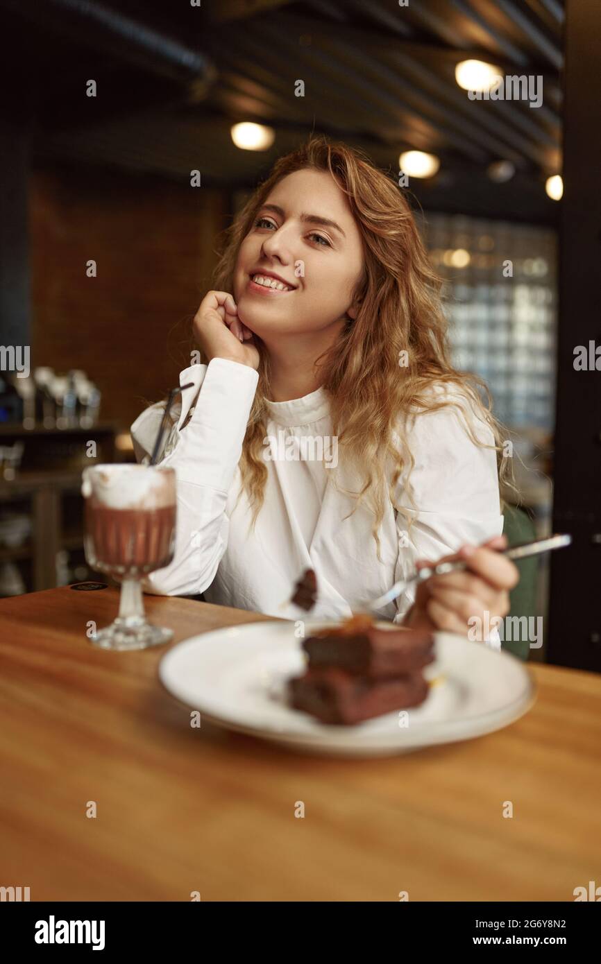 Entspannte Frau, die Kuchen isst und Kakao trinkt Stockfoto