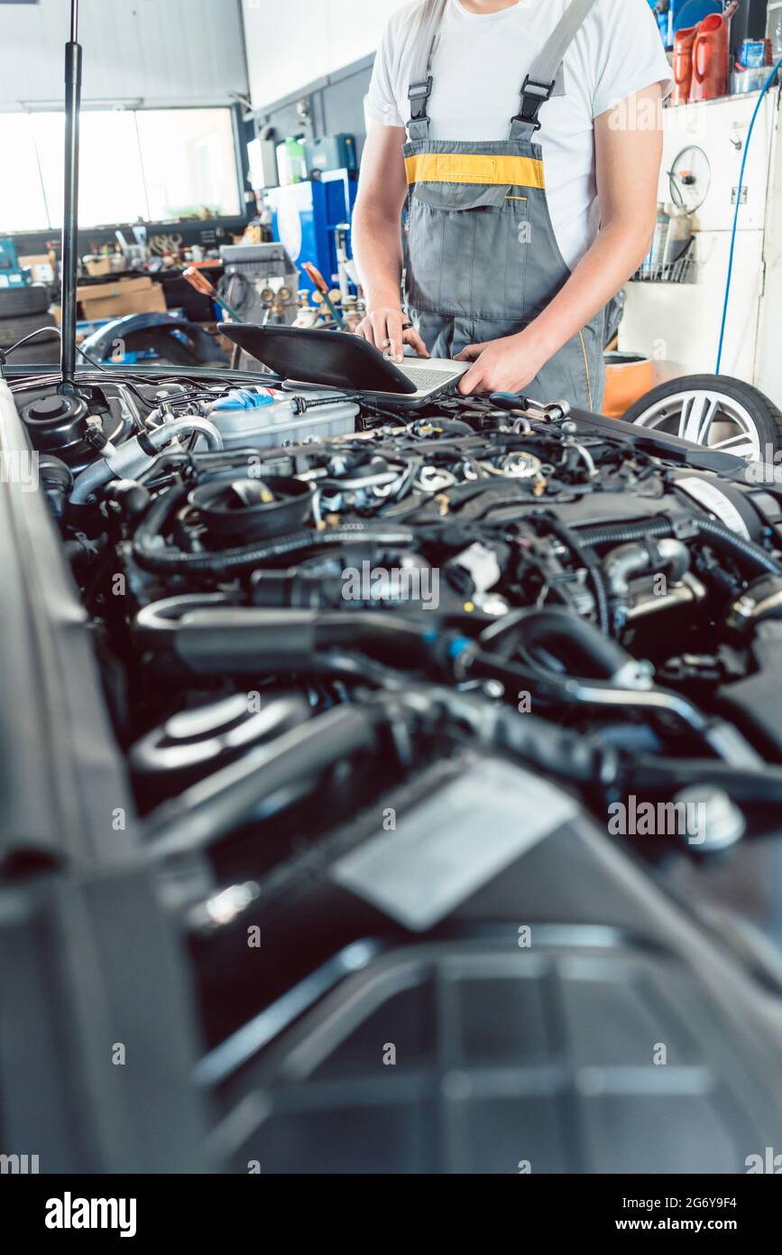 Nahaufnahme eines Schraubendrehers, der von einem erfahrenen Mechaniker vor der Reparatur des Motors gehalten wurde, nachdem die Fehler mit einer Diagnose-Software in einem modernen aut gescannt wurden Stockfoto