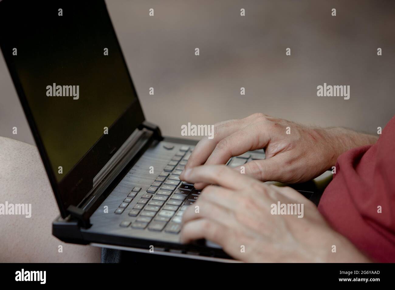 Detail der Hände des Mannes auf der Laptop-Tastatur im Freien Stockfoto