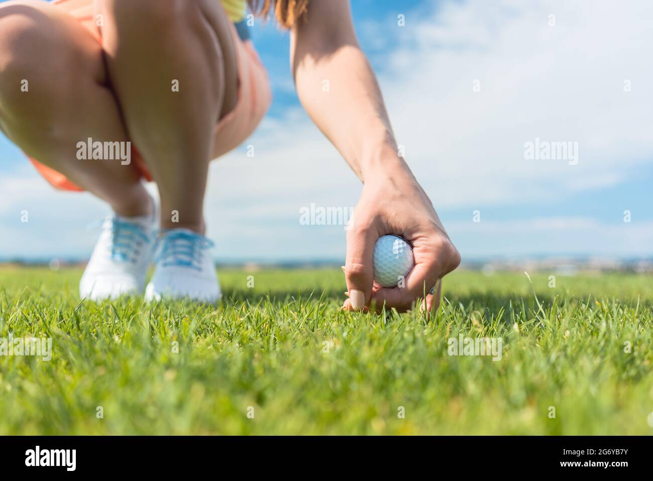 Nahaufnahme der Hand einer Spielerin, die während eines Profispiels an einem sonnigen Tag des Su einen weißen Ball über dem grünen Gras des Golfplatzes hält Stockfoto