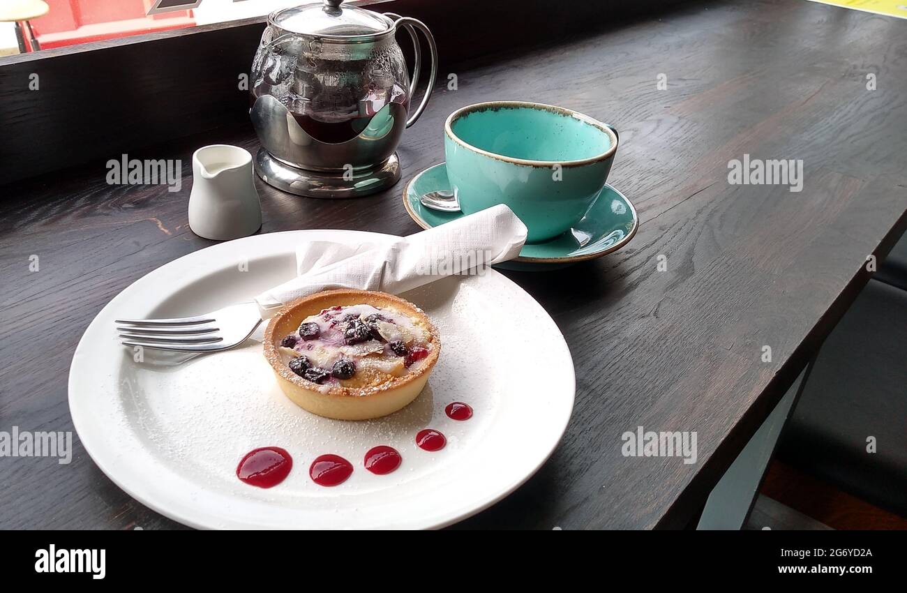 KNUTSFORD. „HES“. ENGLAND. 06-13-21. Eine Kanne Tee und eine rote Johannisbeere in einem Café-Fenster. Stockfoto