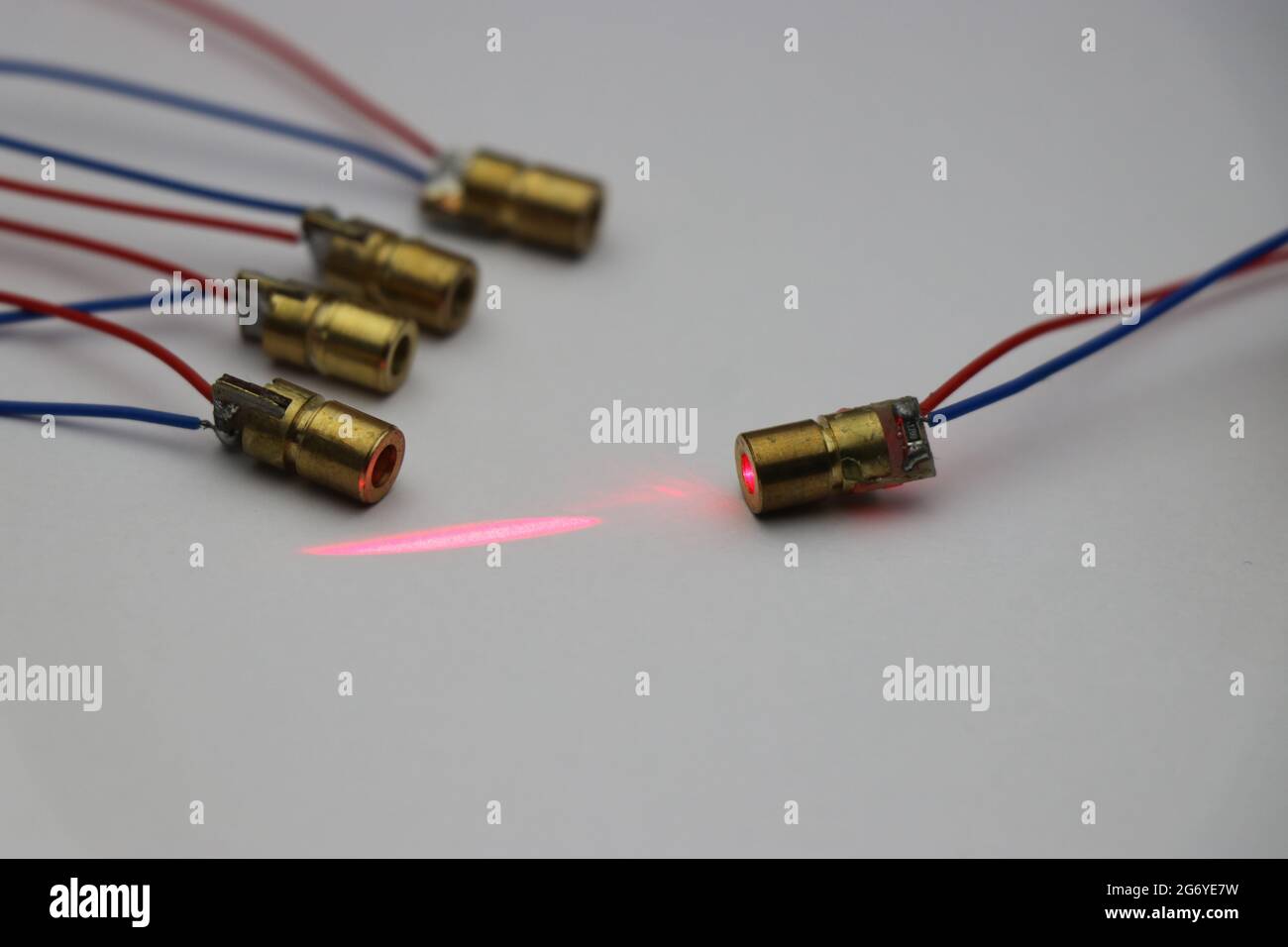 Laserdiode, die klein ist und ein Kupfergehäuse in der Gruppe mit einer Diode hat, die rotes Laserlicht emittiert Stockfoto