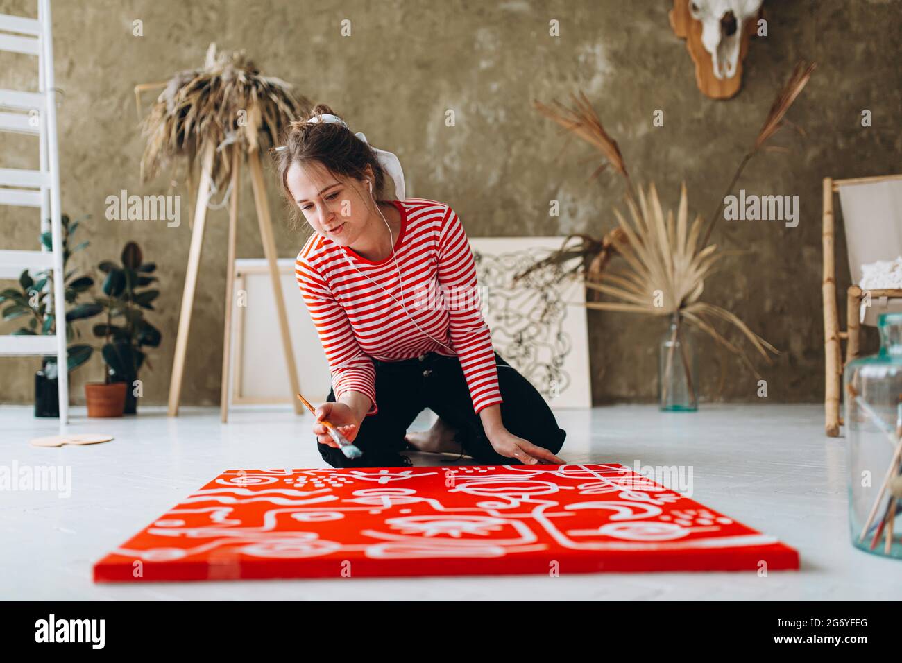 Inspirierter Künstler, der Musik hört und auf Staffelei malt Stockfoto
