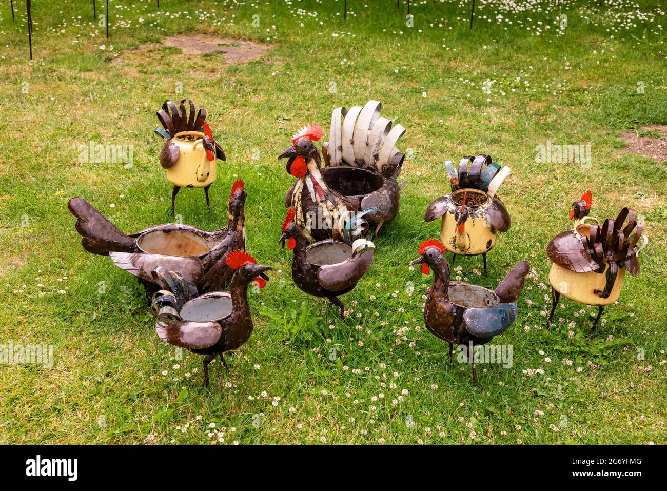 Skurrile Skulpturen von Hühnern aus recycelten Küchentöpfen, die in einem Park ausgestellt sind. Stockfoto