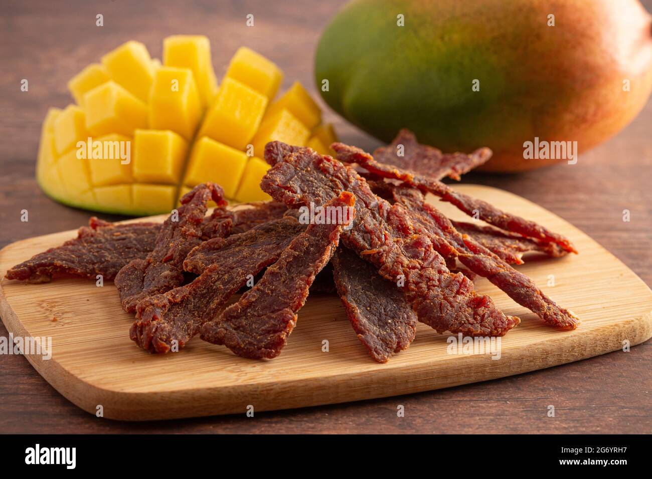 Gourmet Sweet Mango Flavored Beef Jerky auf einem Holzschneidebrettchen Stockfoto