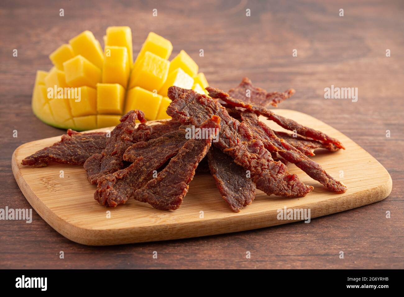Gourmet Sweet Mango Flavored Beef Jerky auf einem Holzschneidebrettchen Stockfoto