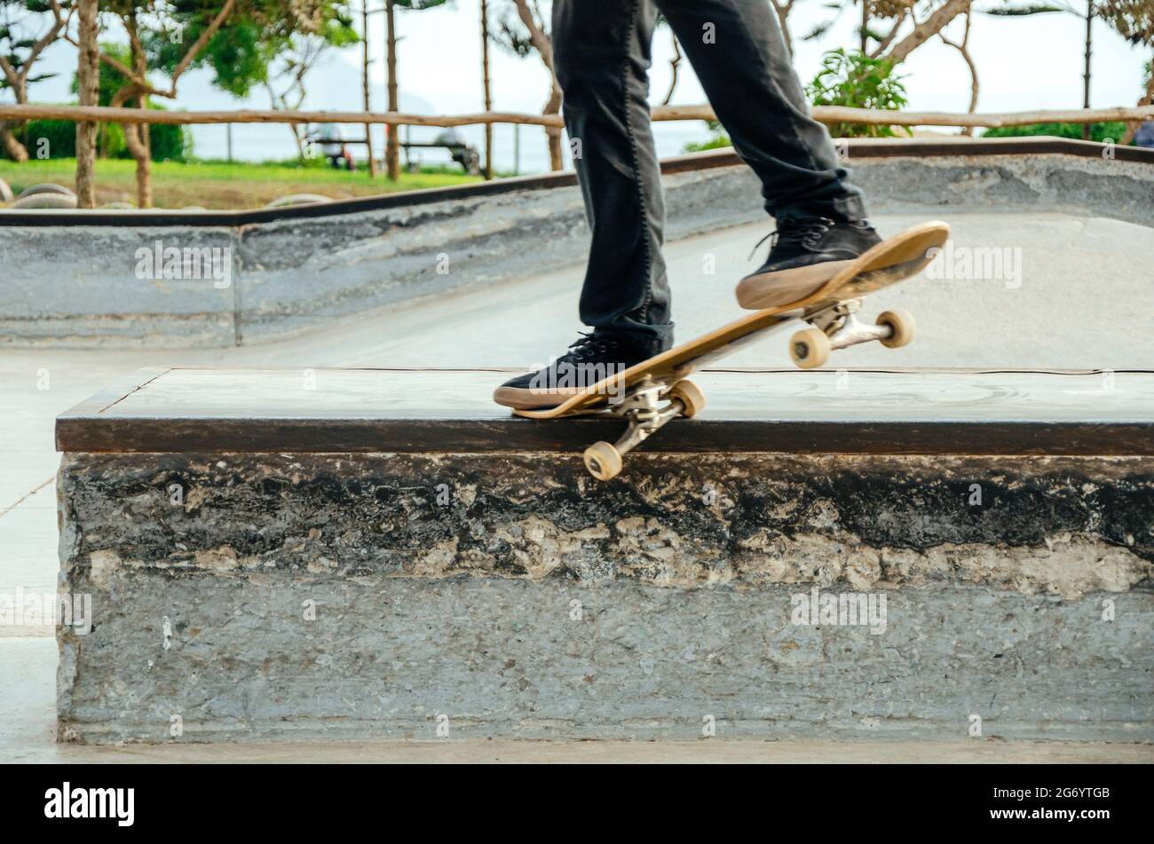 Skateboarder macht einen schrägen Grind-Trick auf einer Bank im Skatepark. Stockfoto