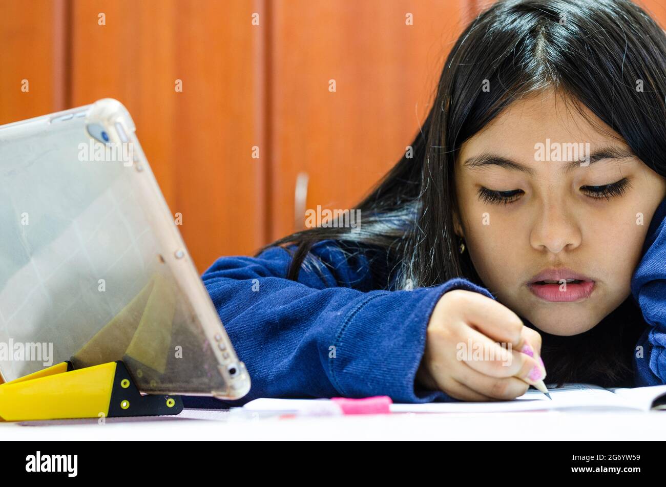 Das Teenager-Schulmädchen macht zu Hause ihre Hausaufgaben mit einem digitalen Tablet. Kind, das Gadgets zum Lernen verwendet. Bildung und Fernunterricht für Kinder Stockfoto