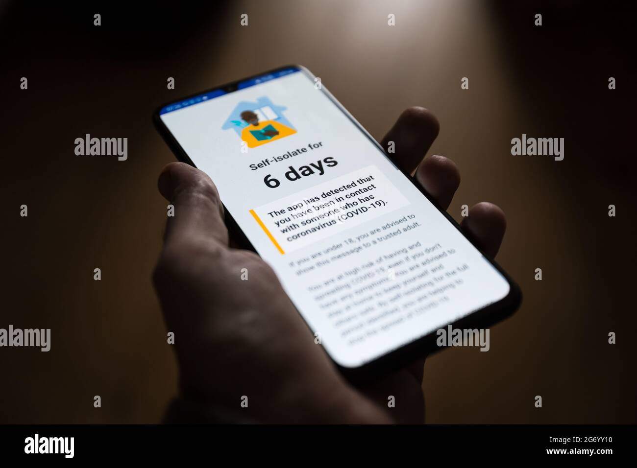 Hand hält ein Handy, das eine Benachrichtigung über eine Selbstisolierungsanforderung von der NHS Track and Trace App nach dem Kontakt mit einer durch Covid infizierten Person anzeigt Stockfoto