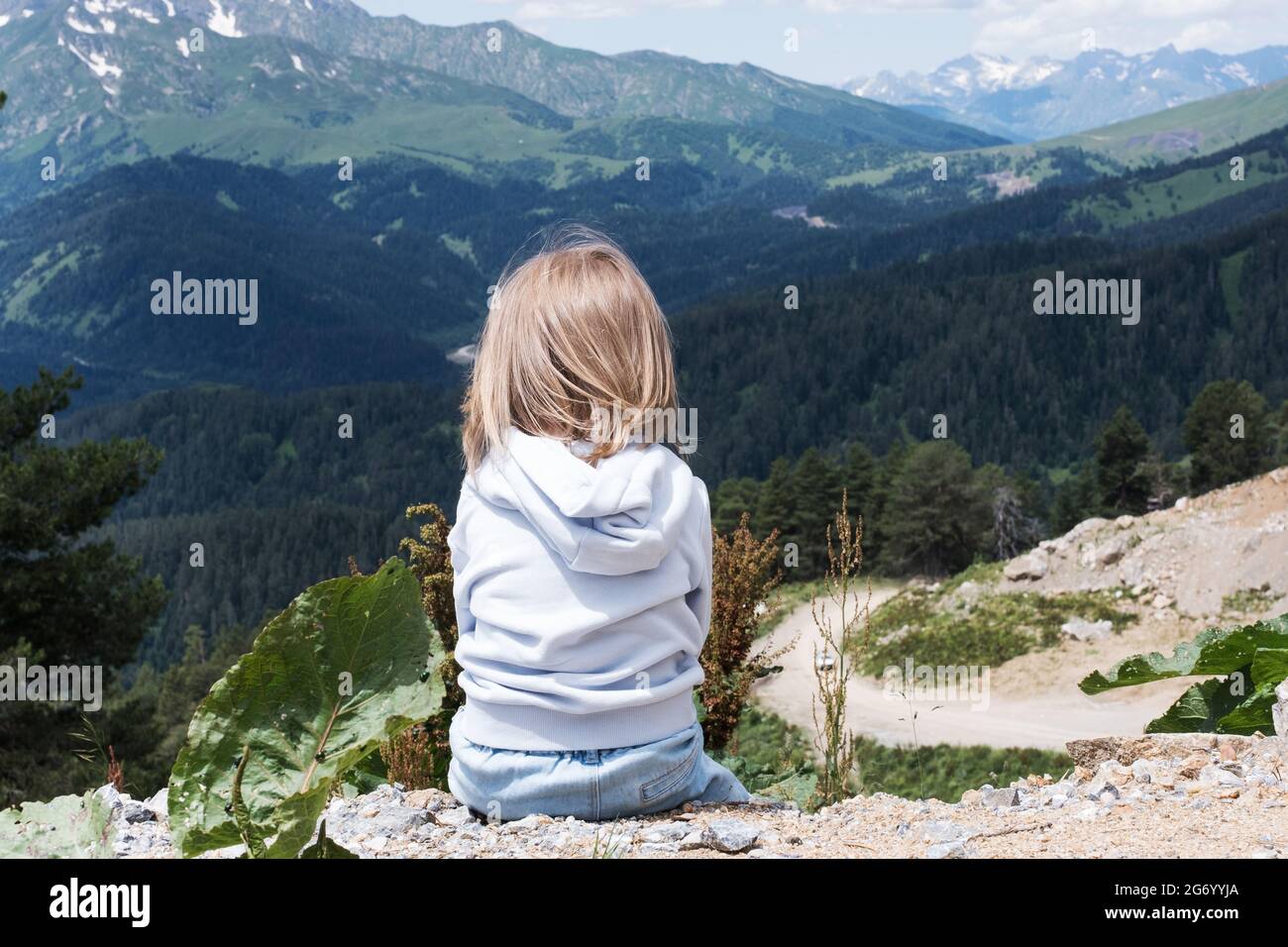 Das Kind sitzt und blickt auf die Landschaft des Kaukasus. Reisen im Freien, Reisen vor Ort. Stockfoto