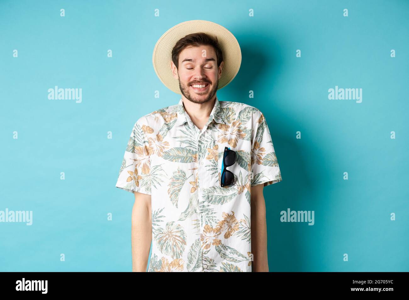 Fröhlicher Tourist, der Sommerurlaub genießt, Strohhut und hawaiihemd trägt  und fröhlich auf blauem Hintergrund steht Stockfotografie - Alamy
