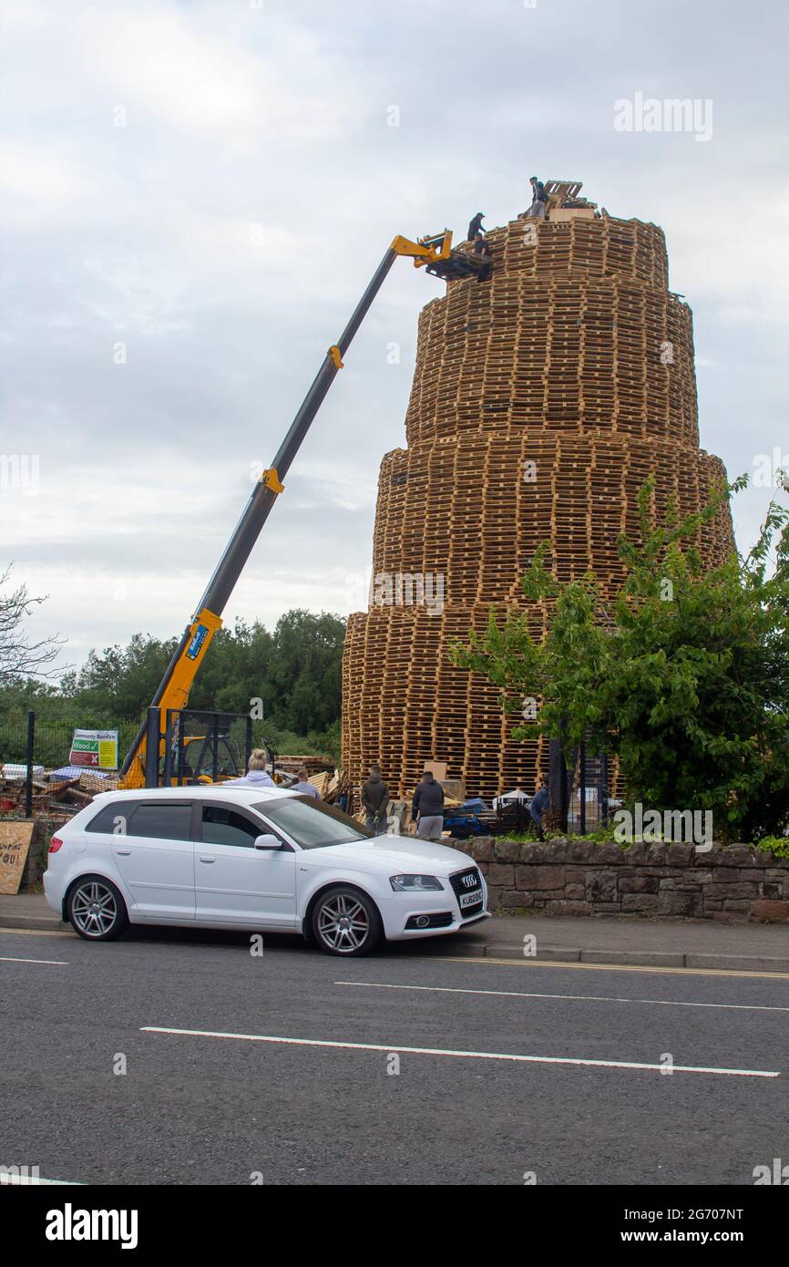 4. Juli 2021 Jugendliche auf dem sehr hohen Lagerfeuer aus tausenden von industriellen Holzpaletten, während sie sich auf die Feierlichkeiten zum 12. Juli vorbereiten Stockfoto
