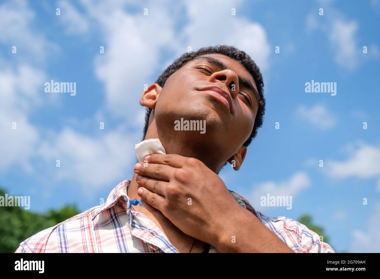 Nasses Wischtuch in den Händen eines jungen brasilianischen Mannes im Freien im Park Stockfoto