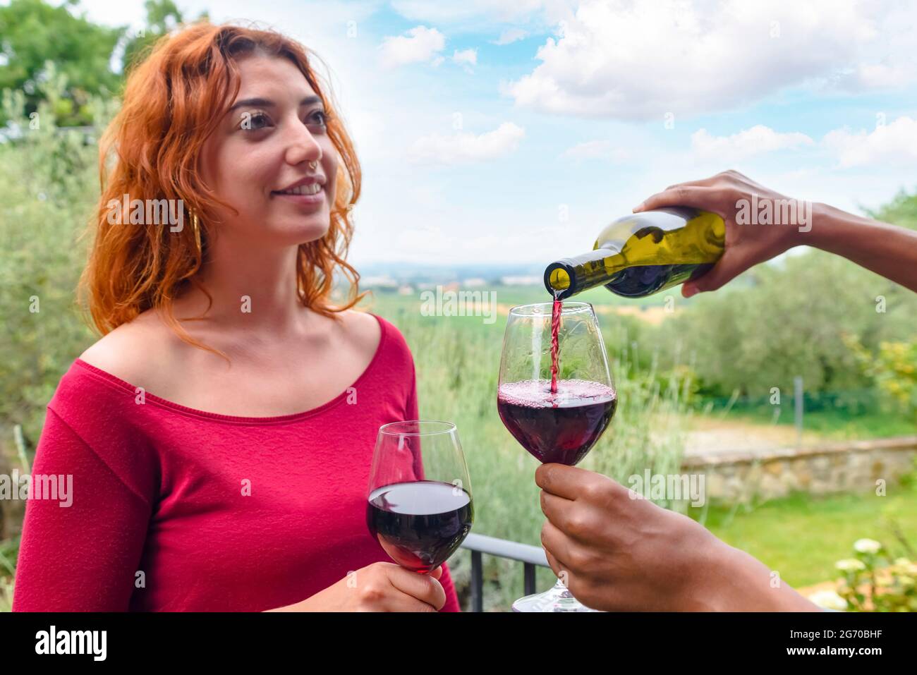 Nahaufnahme Porträt eines vielfältigen Paar im Freien feiert Happy Hour in der Natur. Konzentrieren Sie sich auf das Glas und Hände Gießen Wein. Freunde, die Spaß in t Stockfoto