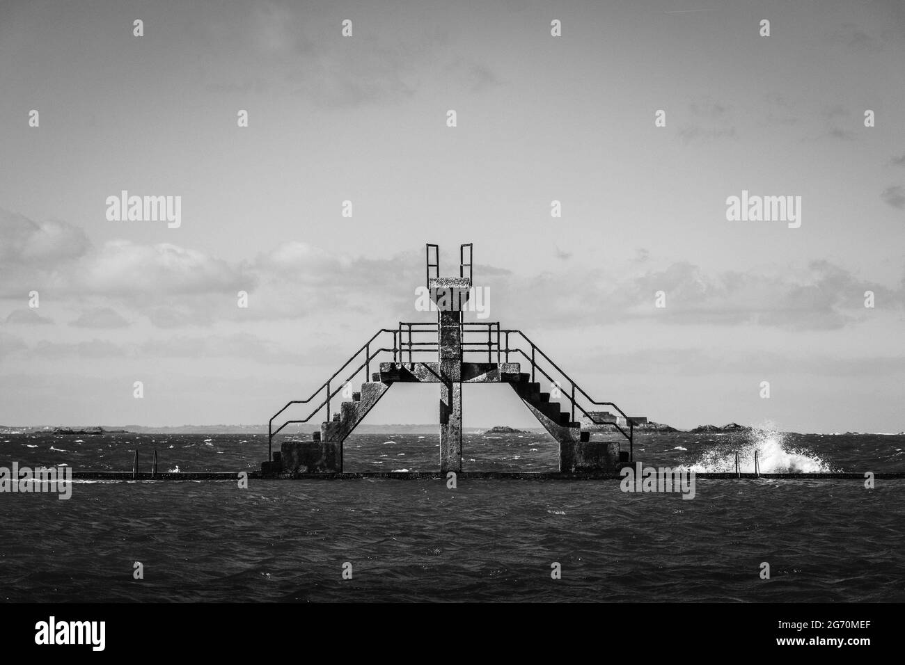 Graustufenaufnahme einer alten Fußgängerbrücke über das Meer Stockfoto
