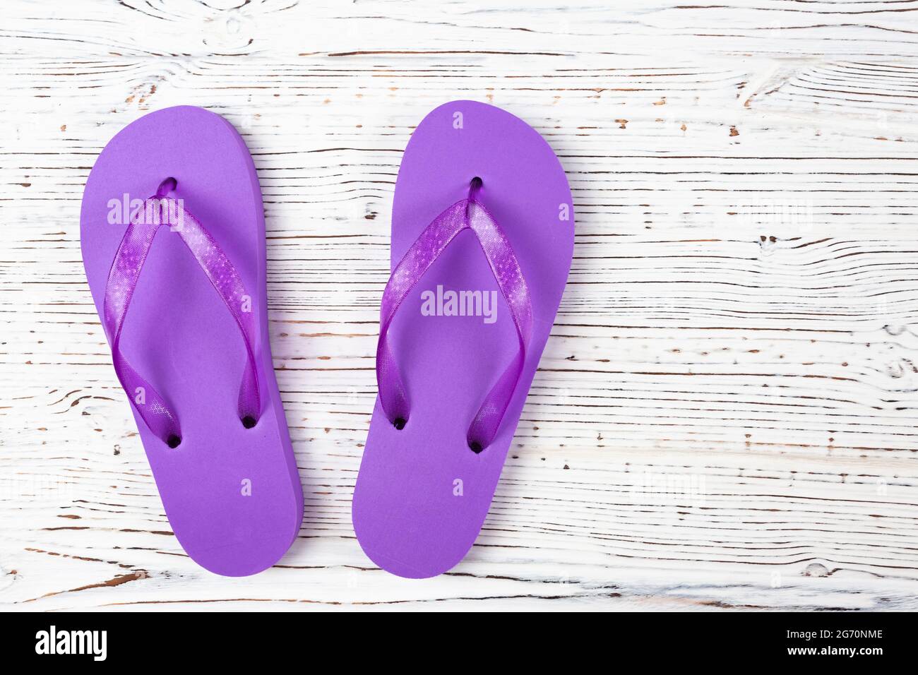 Lila Gummi-Flip-Flops auf weißem Holzhintergrund, Draufsicht, Platz für Text Stockfoto