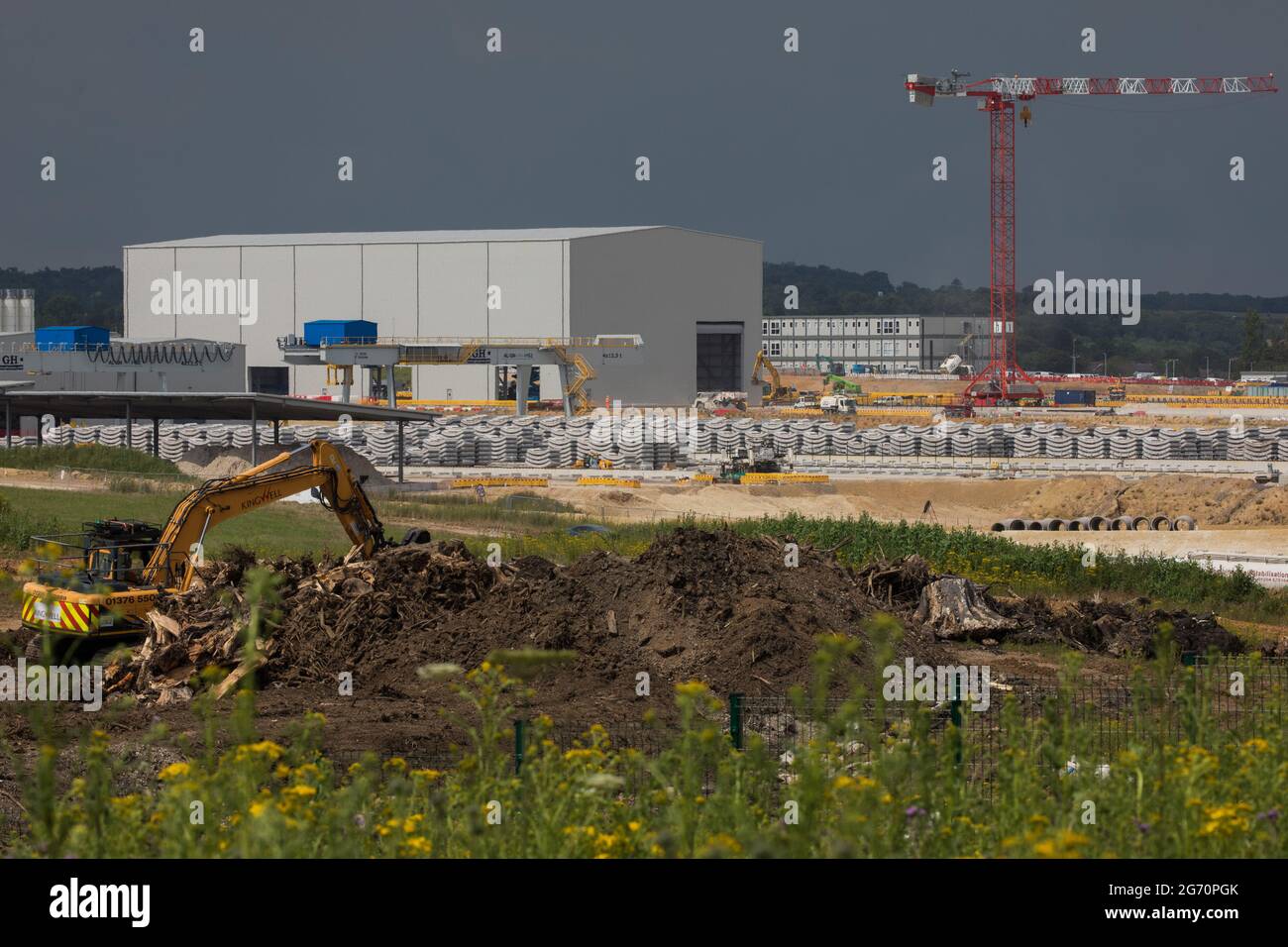 West Hyde, Großbritannien. Juli 2021. Ein Bagger bewegt die Überreste von gefällten Bäumen vor präzisionsgefertigte Tunnelsegmente am Standort South Portal für den Tunnelabschnitt Chiltern der Hochgeschwindigkeitsstrecke HS2. HS2 Ltd hat den Start der zweiten 2,000-Tonnen-Tunnelbohrmaschine (TBM) bekannt gegeben, die Cecilia nach der Astronomin und Astrophysikerin Cecilia Payne-Gaposchkin benannt wurde, um einen zweiten 10-Meilen-Tunnel unter den Chilterns auszugraben. Kredit: Mark Kerrison/Alamy Live Nachrichten Stockfoto