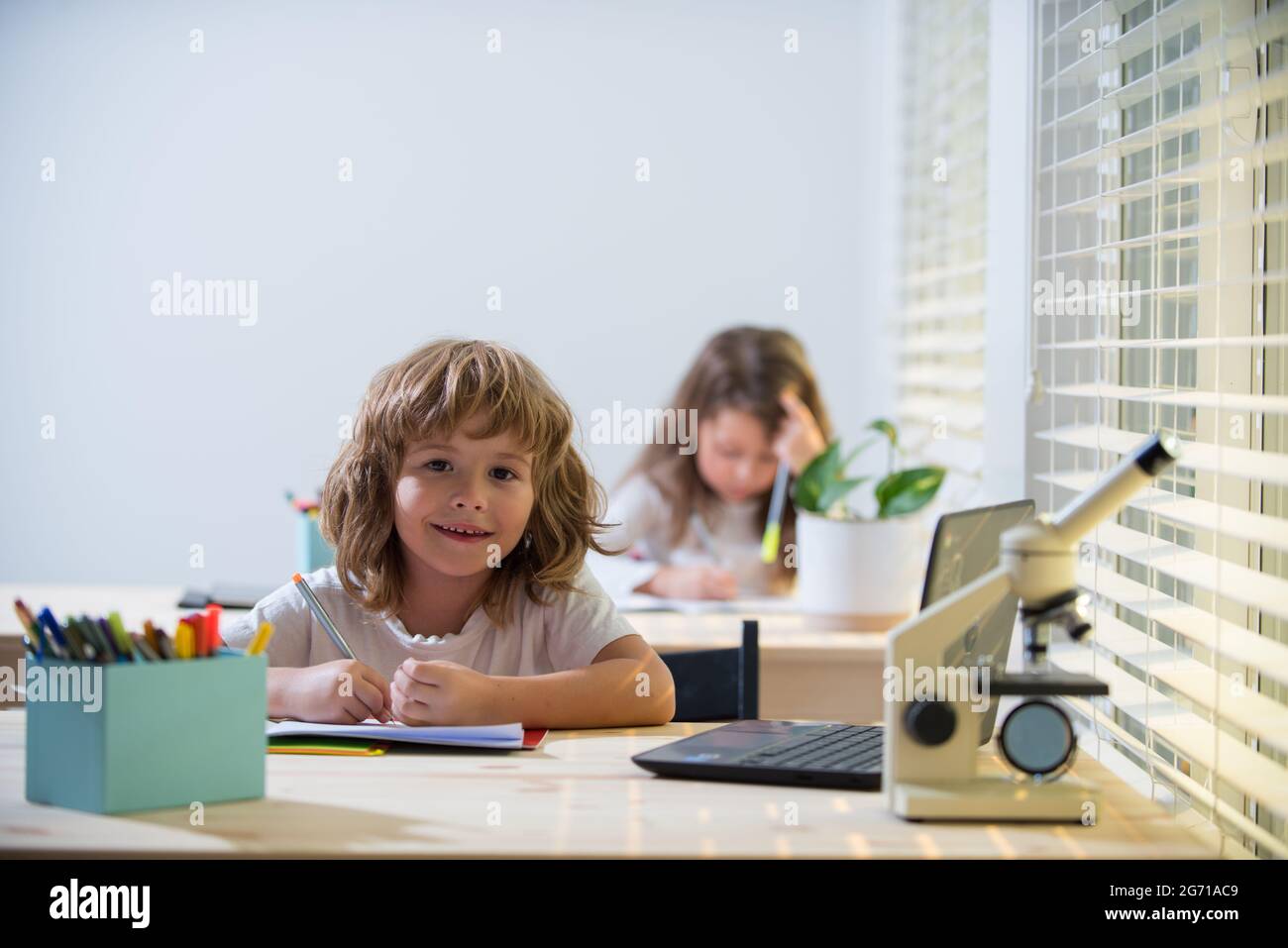Schuljunge sitzt am Tisch, schreibt Hausaufgaben oder bereitet sich auf die Prüfung vor. Kinderstudie. Kleine Studenten lernen. Stockfoto