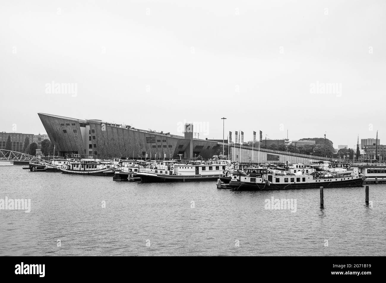 AMSTERDAM, NIEDERLANDE. 06. JUNI 2021. Schöner Blick auf einen Schiffskanal und Brücken. Schwarzweiß-Fotografie. Kleine Boote, Schiffe und Bargen Stockfoto