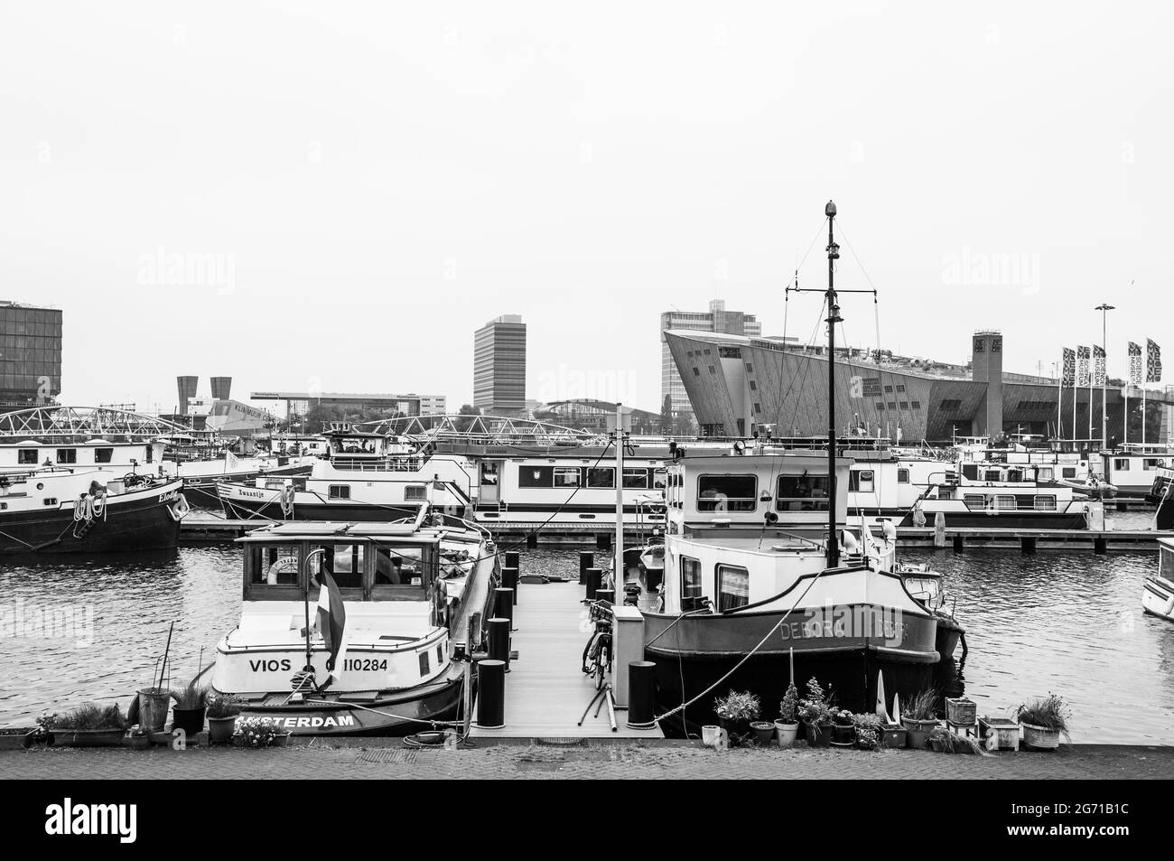 AMSTERDAM, NIEDERLANDE. 06. JUNI 2021. Schöner Blick auf einen Schiffskanal und Brücken. Schwarzweiß-Fotografie. Kleine Boote, Schiffe und Bargen Stockfoto