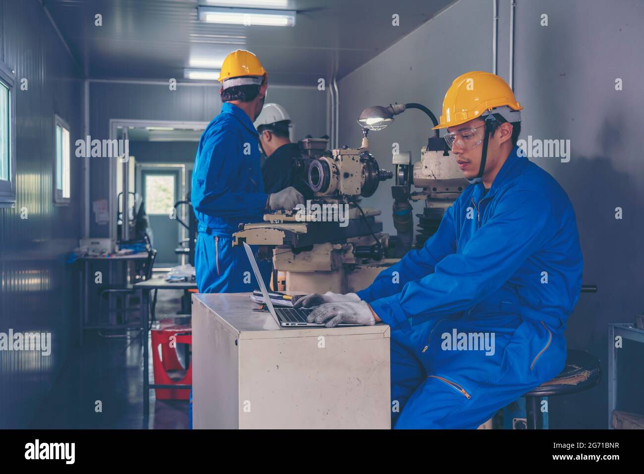 Maschinist, der einen Schutzhandschuh trägt, schützt die Augen beim Einsatz der Tischschleifmaschine für die Metallbearbeitung. Mann, der die Drehbank der Schleifmaschine Me betreibt Stockfoto
