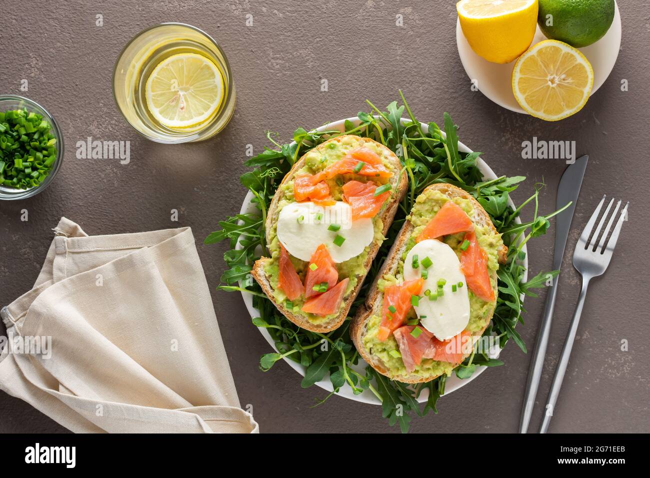 Leckeres herzhaftes Frühstück, Sandwiches mit Avocado-Paste, Lachs und Mozzarella auf einem Teller mit Rucola und Erbsensprossen Stockfoto