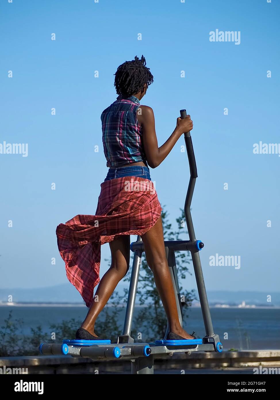 Schwarze Frau mit rotem Rock auf einem Stepper im Freien in Lissabon Stockfoto