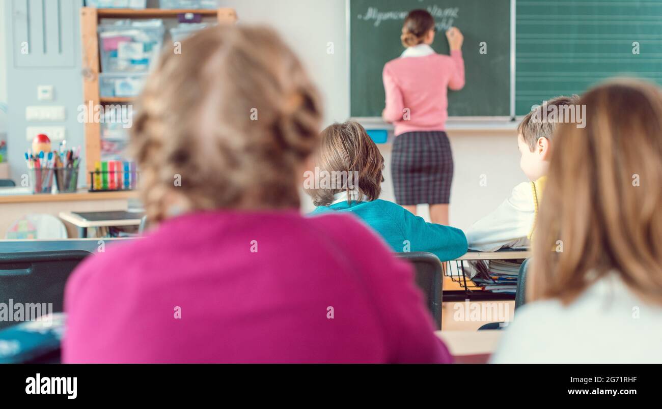 Lehrer in der Klasse mit Schülern der vierten Klasse vor der schwarzen Tafel, Bildung ist so wichtig, dass ich es erfahren habe Stockfoto
