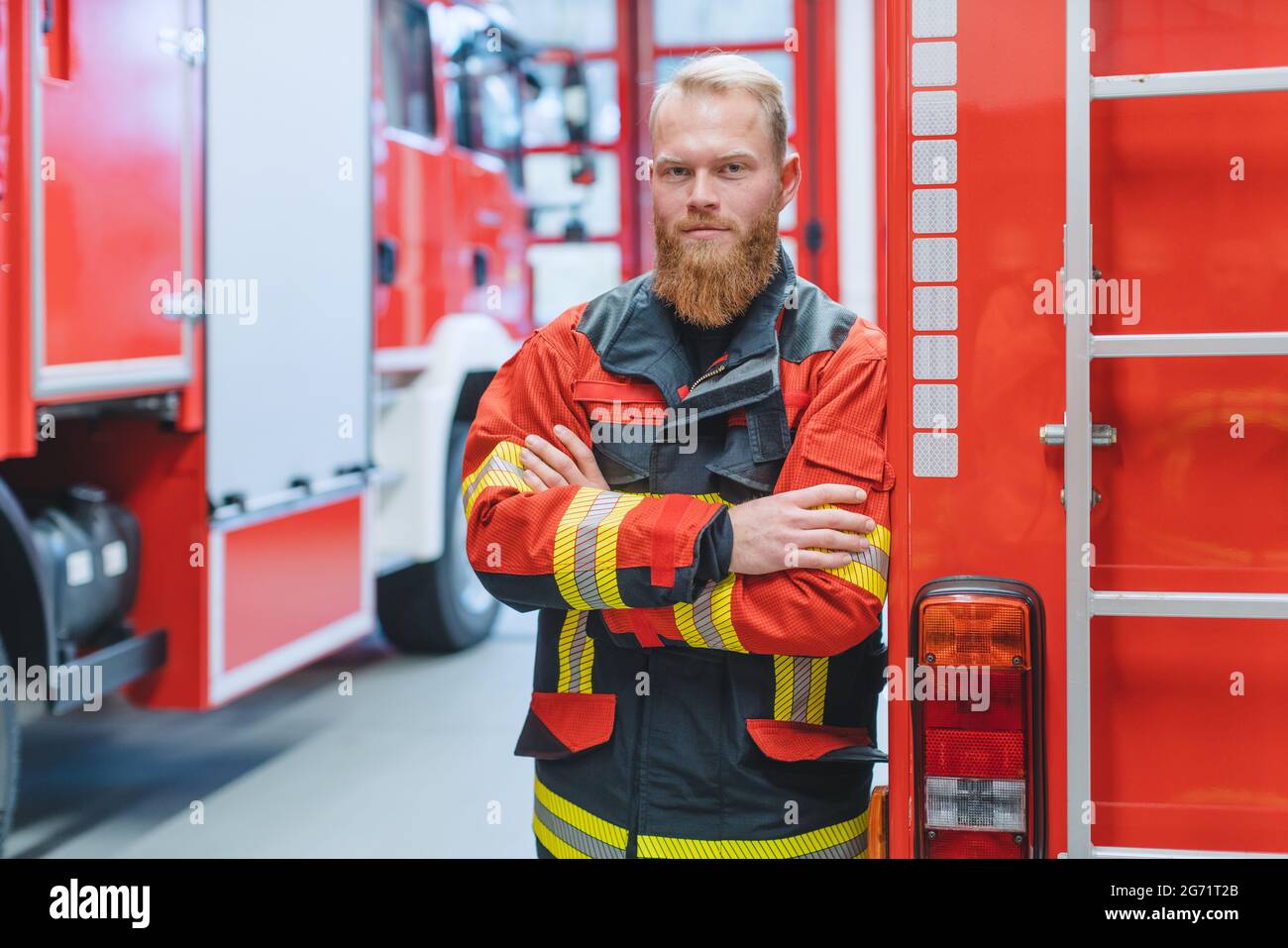 Entschlossener junger Feuerwehrmann vor einem Feuerwehrauto In der Aufseherin Stockfoto