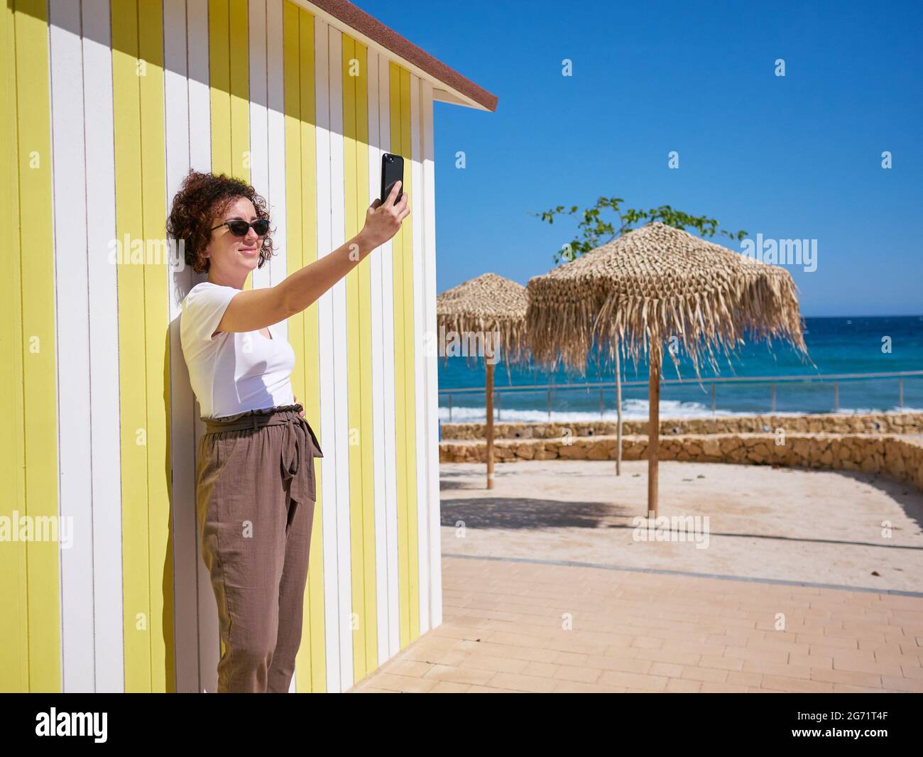 Frau, die während ihres Sommerurlaubs ein Selfie mit ihrem Mobiltelefon macht Stockfoto