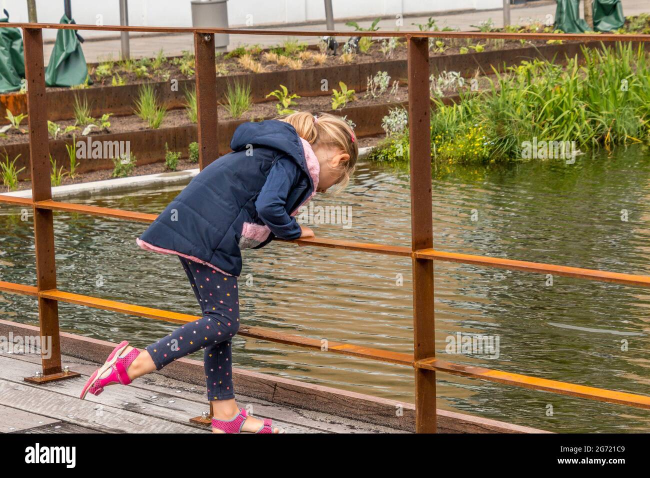 Randers, Dänemark - 10-Juli-2021: Mädchen schaut in das Wasser des neuen Regenwasserbeckens bei Ostervold in Randers. Stockfoto