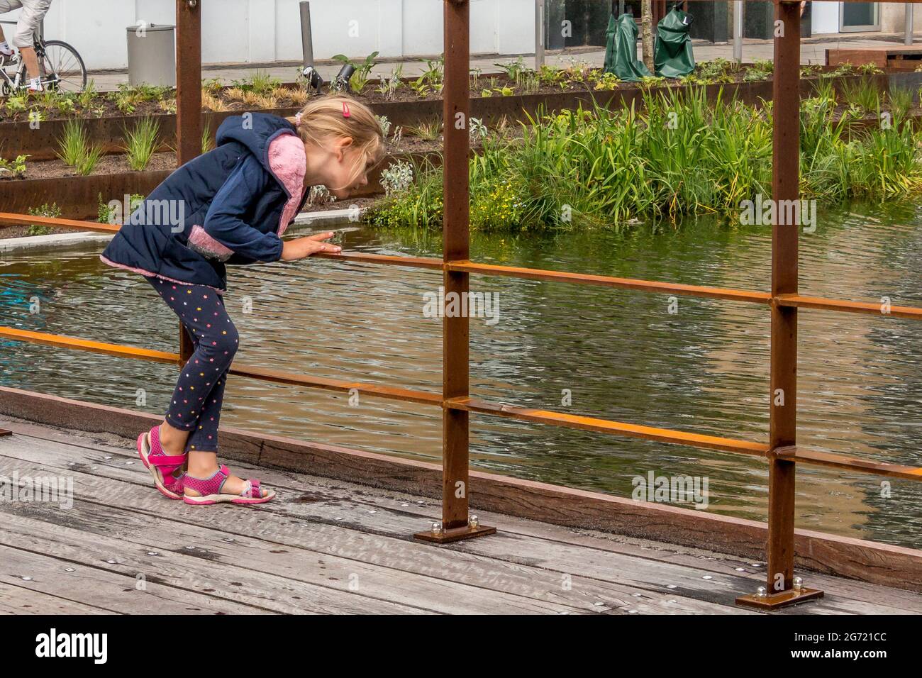 Randers, Dänemark - 10-Juli-2021: Mädchen schaut in das Wasser des neuen Regenwasserbeckens bei Ostervold in Randers. Stockfoto
