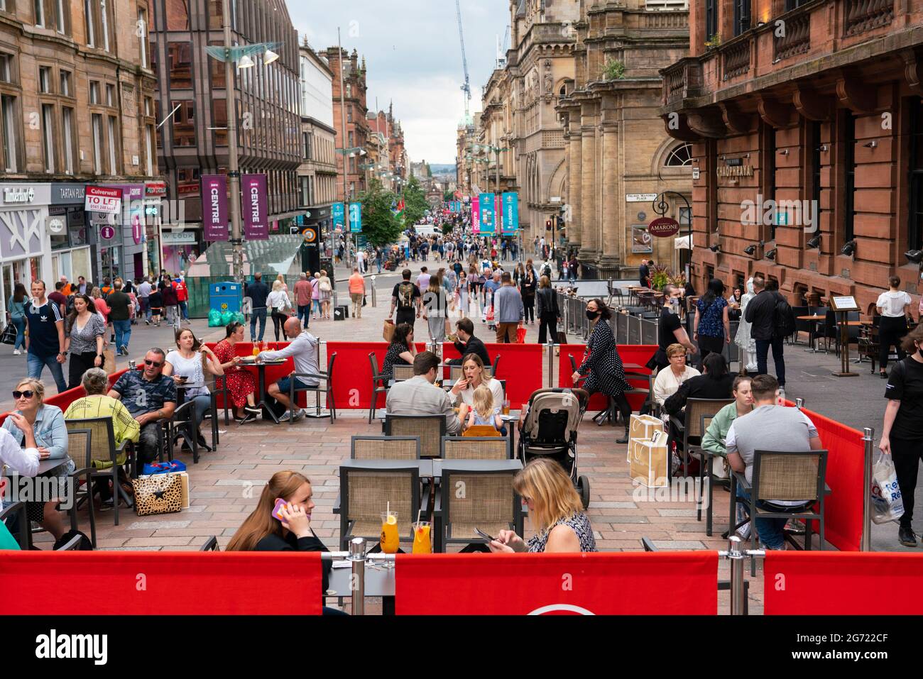 Glasgow, Schottland, Großbritannien. 10. Juli 2021. Mitglieder der öffentlichen Einkaufs- und Restaurantmöglichkeiten in Cafés an der Buchanan Street an einem warmen Samstagnachmittag im Stadtzentrum von Glasgow. Das gute Wetter brachte viele Menschen ins Stadtzentrum, um die vielen Cafés und Bars zu nutzen, die auf den Bürgersteigen auf den Straßen der Stadt Sitzgelegenheiten im Freien eingerichtet haben. Iain Masterton/Alamy Live Nachrichten. Stockfoto