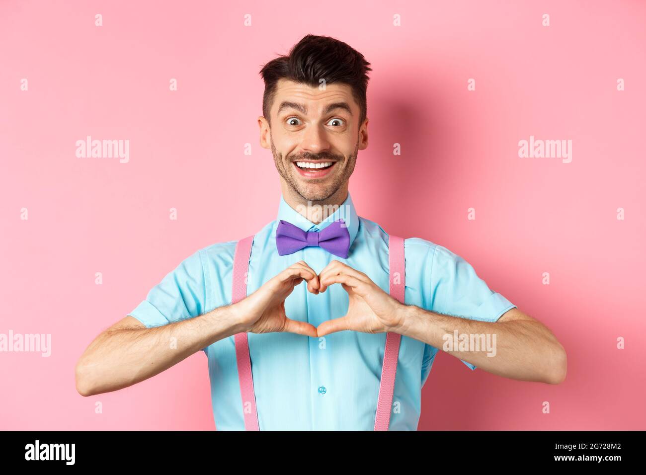 Alles gute zum Valentinstag. Lächelnder lustiger Kerl mit Schnurrbart, der Herzzeichen zeigt und den Geliebten anschaut, sagt, ich liebe dich, drücke Gefühl aus, überstehend Stockfoto