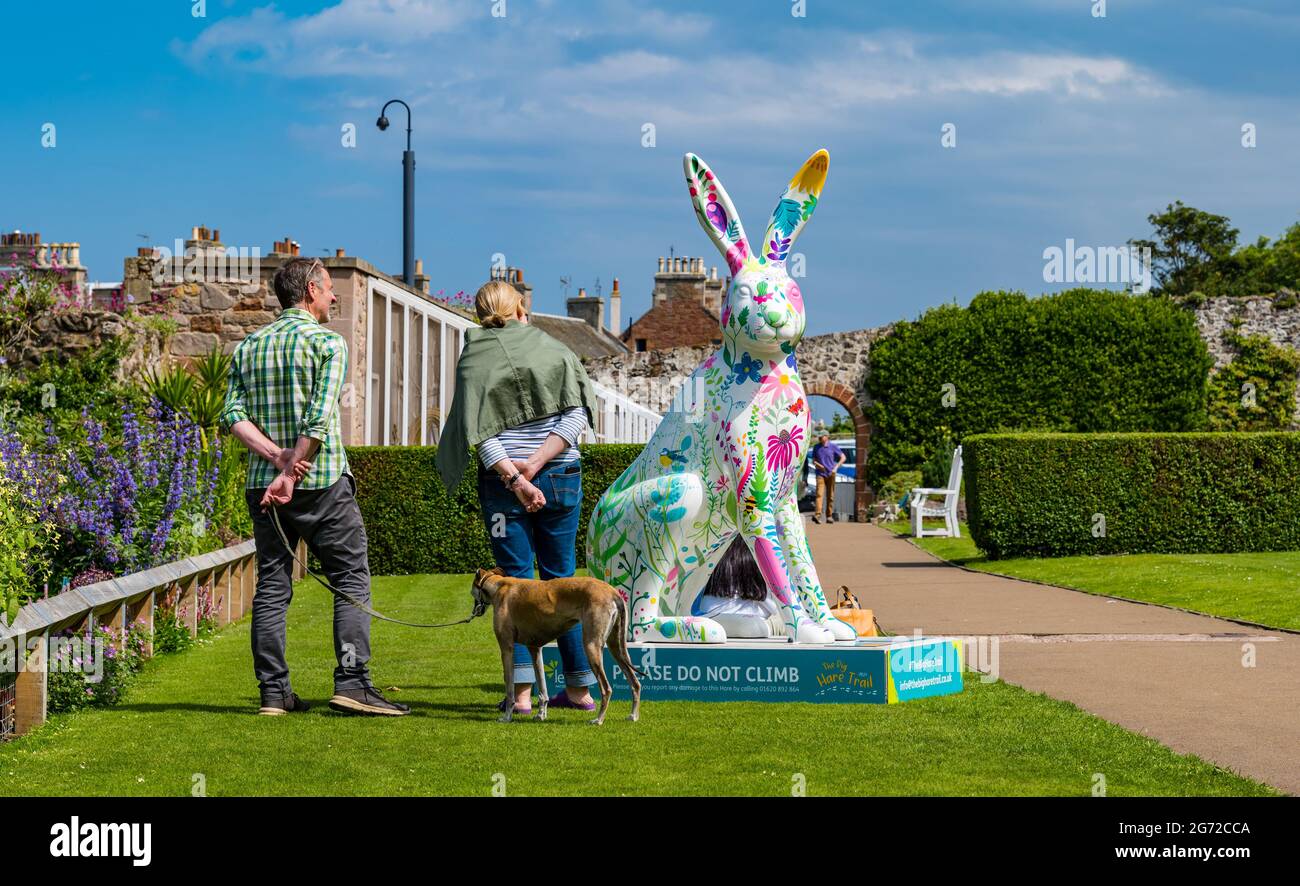 North Berwick, East Lothian, Schottland, Großbritannien, 10. Juli 2021. Der Big Hare Trail: Der Trail beginnt heute und dauert 11 Wochen mit 10 riesigen, handgemalten Hasen-Skulpturen, die jeweils von einem anderen Künstler in der Küstenstadt stammen. Organisiert wird es von Leuchie House, einer Wohltätigkeitsorganisation für Menschen mit neurologischen Erkrankungen. Im Bild: Die Menschen bewundern einen Hasen, der von Rosie Watson gemalt wurde, im Park des Lodge Grounds Stockfoto