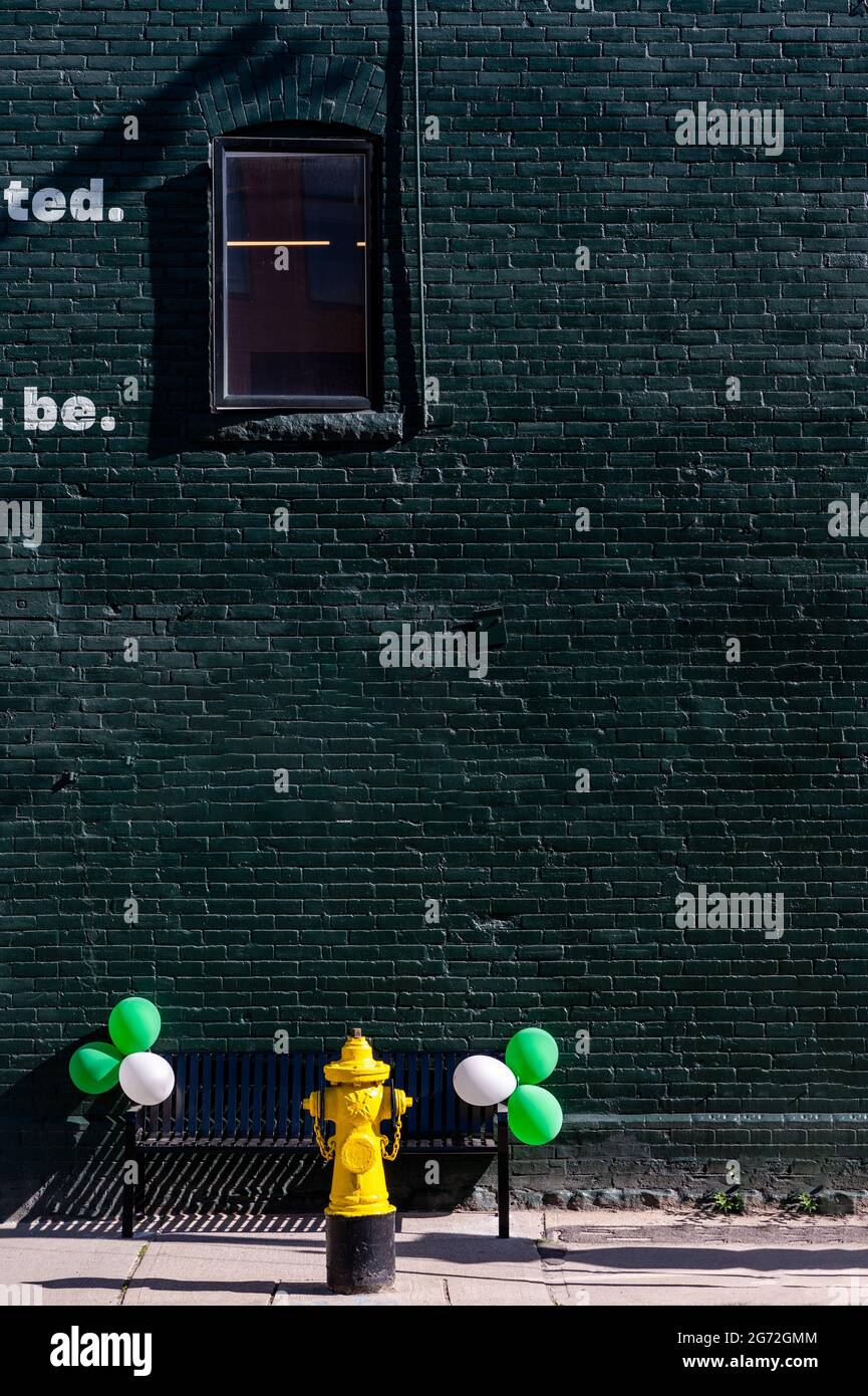 Vertikale Aufnahme einer Backsteinmauer in grün lackiert und Ballons in Ton in der Nähe platziert Stockfoto