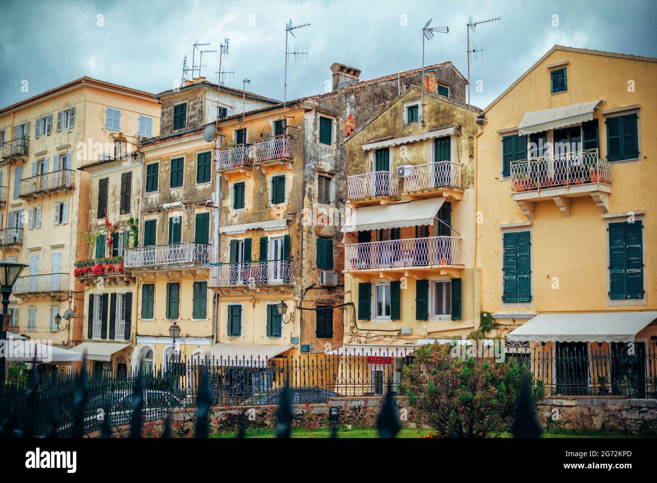 Korfu-Insel/Griechenland - 4. Mai 2019: Blick auf alte und verwitterte Gebäudefassaden - Wand mit geschälter Farbe, grüne Holzläden an den Fenstern. Kerkyra o Stockfoto
