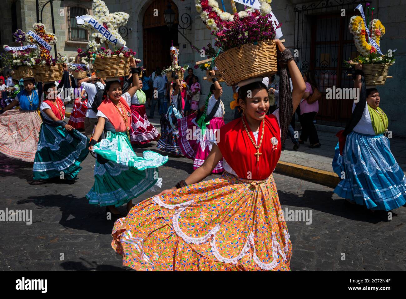 Oaxaca de Juarez, Mexiko - 15. Mai 2014: Eine Gruppe von Frauen in traditionellen bunten Kleidern und Körben mit Blumen, die auf einer Straße tanzen Stockfoto