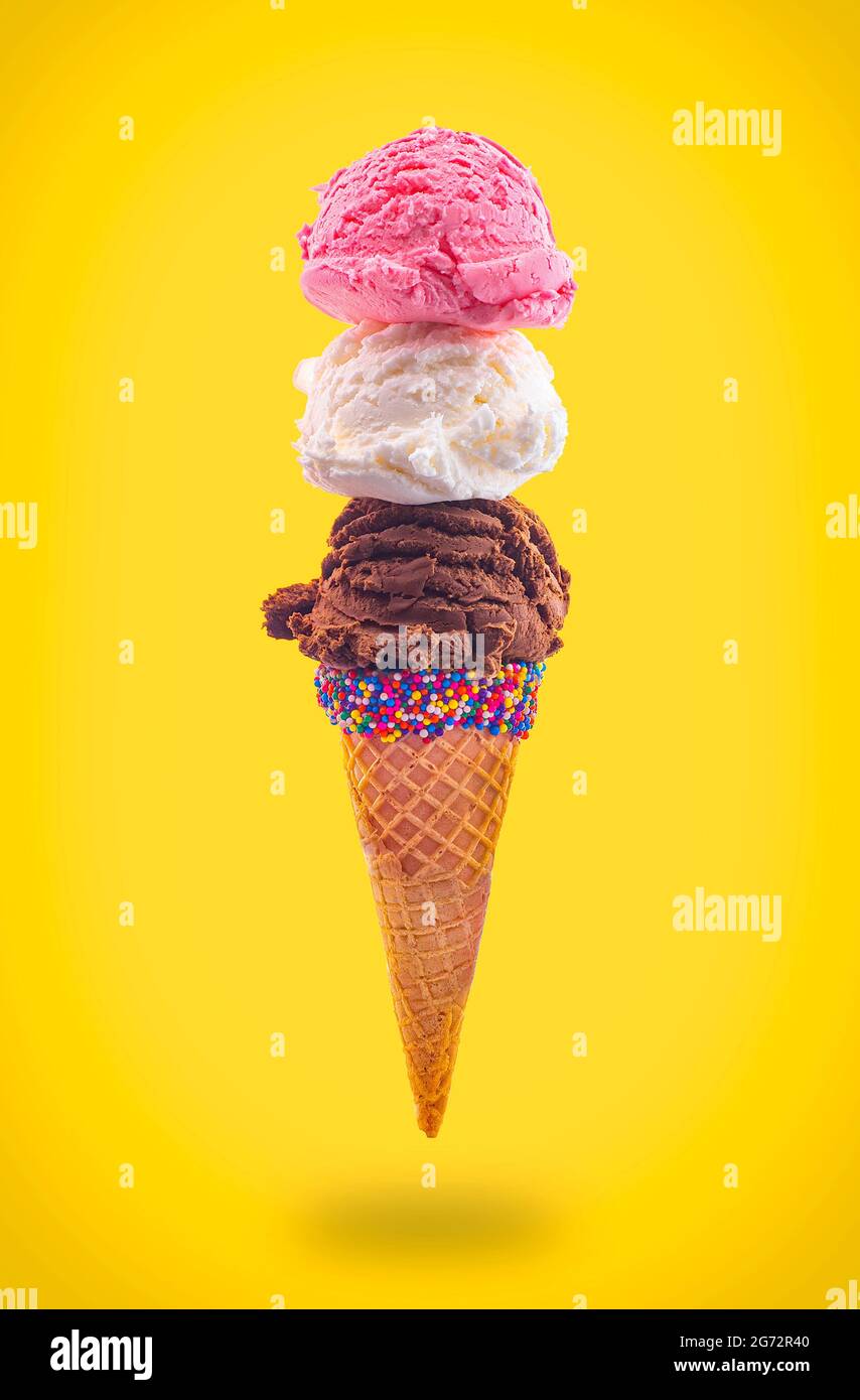 Eiskegel mit Erdbeer-Vanille und Schokolade in einem spitzen Zuckerkegel, der in der Luft schwimmt Stockfoto