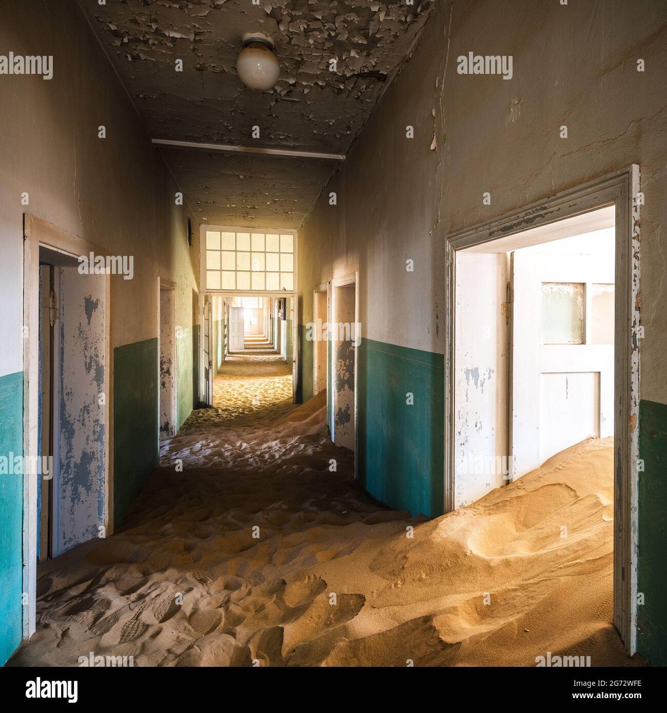 Verlassene Gebäude, die in der alten Bergbaustadt Kolmanskop in der Nähe von Luderitz, Namib-Wüste, Namibia, von eindringenden Sand übernommen wurden. Stockfoto