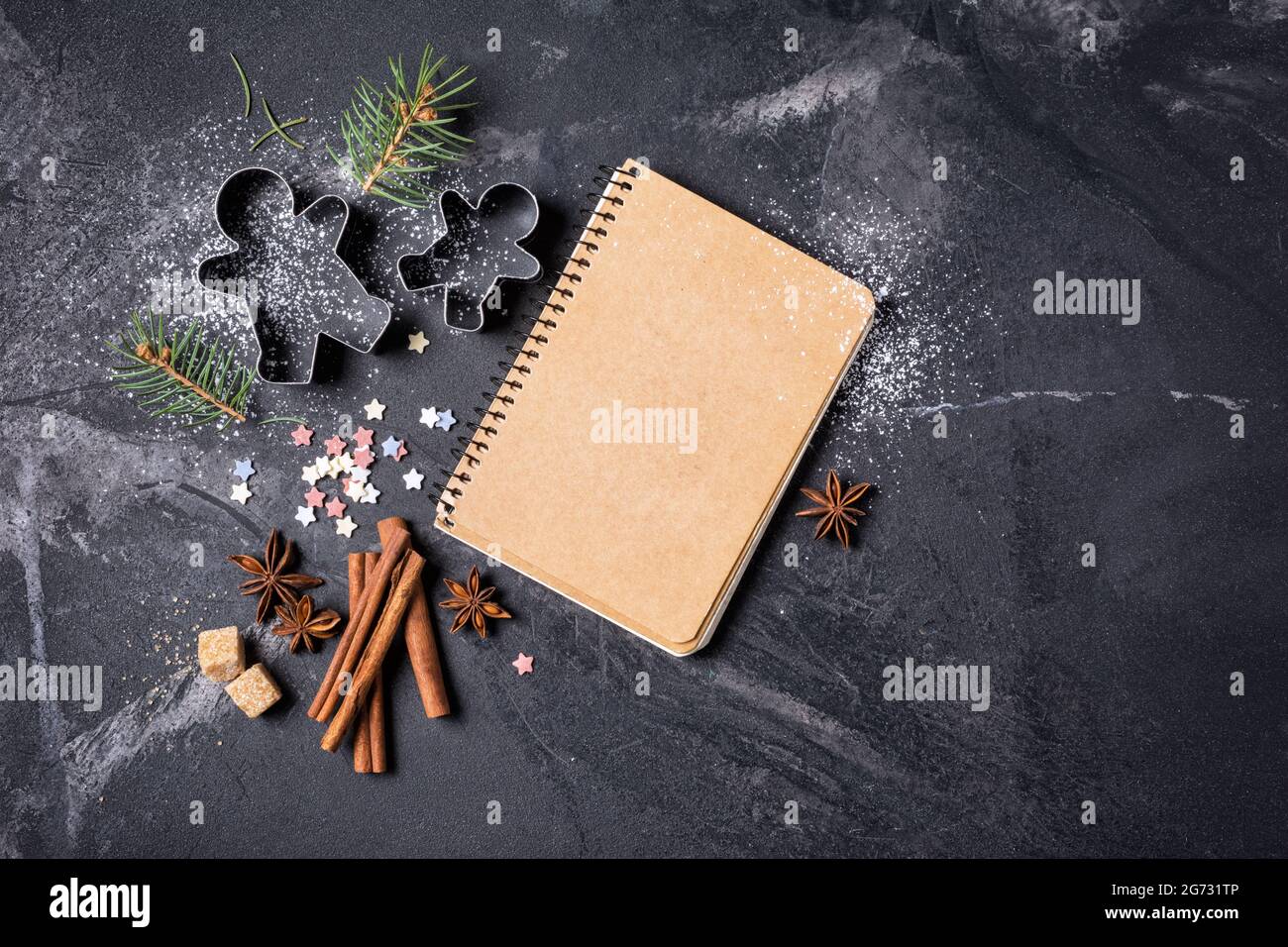 Draufsicht auf Mockup-Notizblock für Rezept- und weihnachtliche Backzutaten auf schwarzem Marmorhintergrund mit Kopierfläche Stockfoto