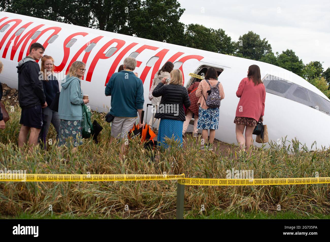 East Molesey, Surrey, Großbritannien. Juli 2021. Die Menschen stehen Schlange, um den sehr beliebten Global Impact Garden, Extinction von Designr Felecity O'Rourke, zu sehen. Es war ein sehr geschäftiger Tag heute am 4. Tag des RHS Hampton Court Palace Garden Festivals. Im echten britischen Stil schien die Sonne am Morgen, aber am Nachmittag folgten heftige Duschen, da Sonnenschirme und Ponchos die Accessoires waren, die man unbedingt haben sollte. Quelle: Maureen McLean/Alamy Stockfoto