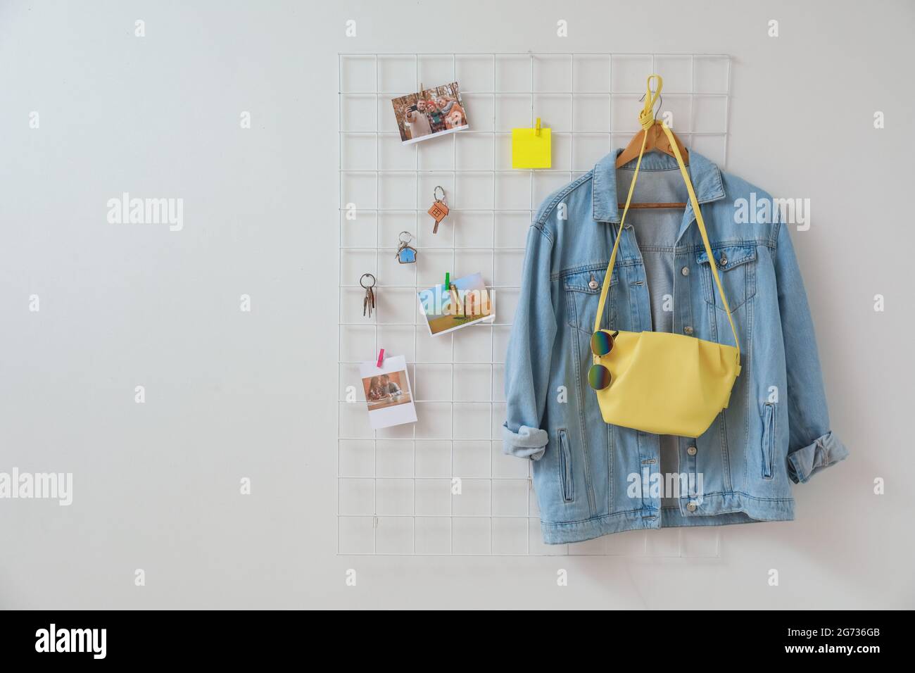 Halter mit Schlüsseln, Kleidung und Bildern, die an der hellen Wand hängen Stockfoto
