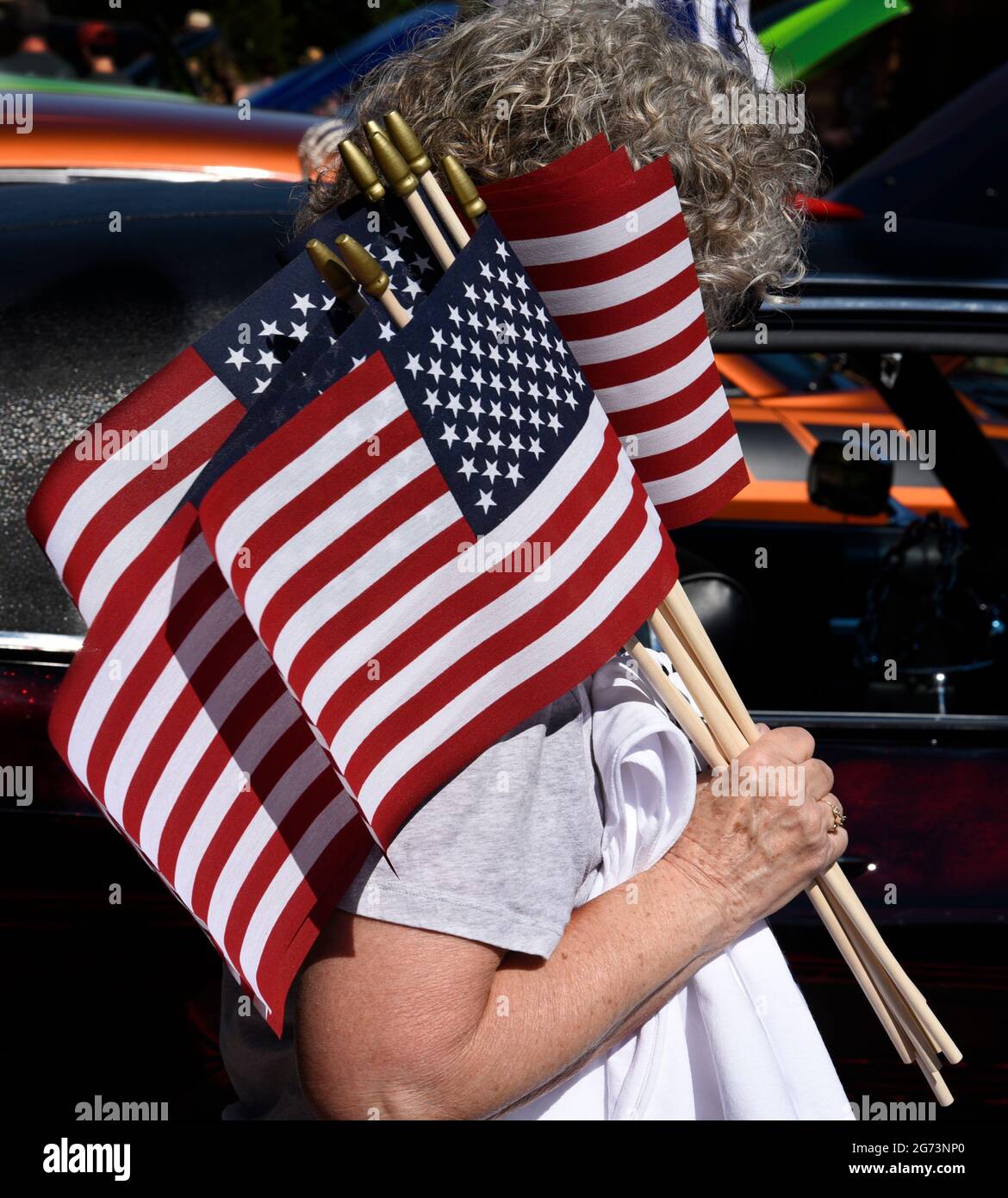 Eine Frau verteilt kleine amerikanische Flaggen auf einer Oldtimermesse am 4. Juli in Santa Fe, New Mexico. Stockfoto