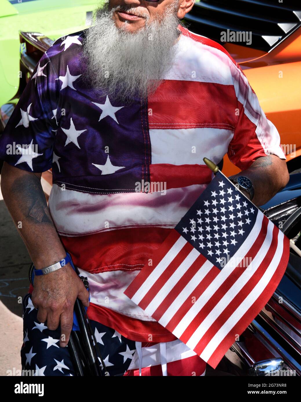 Ein Mann, der in den Farben und im Design der amerikanischen Flagge gekleidet ist, besucht eine Oldtimer-Show am 4. Juli in Santa Fe, New Mexico. Stockfoto