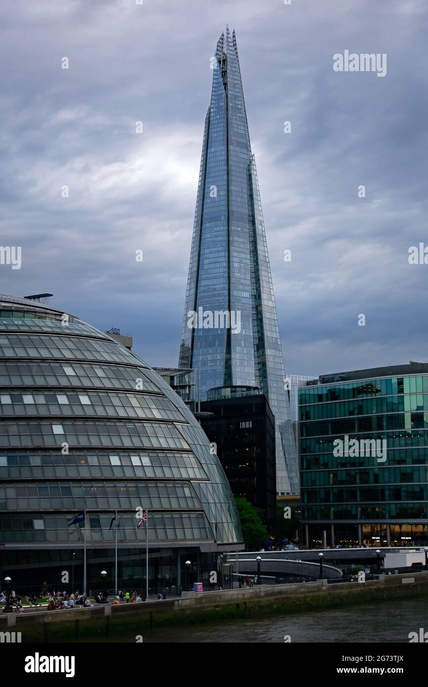 Ein Blick auf den Shard und das Rathaus von der Tower Bridge in der Abenddämmerung in London, England. Die Wolkendecke scheint hinter dem Wolkenkratzer zu brechen. Stockfoto