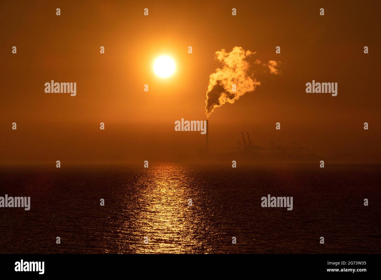 Sonnenuntergang und Dampf. Die Sonnenuntergänge während Dampf aus dem Kamin eines Kraftwerks in Melbourne Australien steigt. Stockfoto