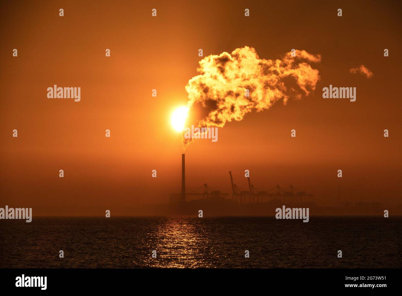 Sonnenuntergang und Dampf. Die Sonnenuntergänge während Dampf aus dem Kamin eines Kraftwerks in Melbourne Australien steigt. Stockfoto